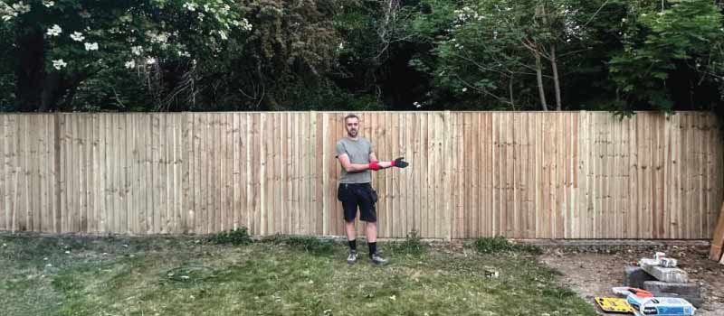 Leonard, fencing contractor, standing in front of a completed closeboard fence installation near Henley-on-Thames